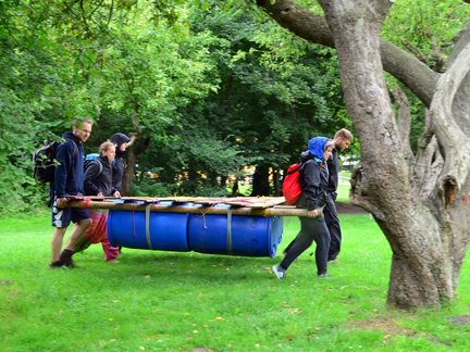 Gruppe trägt Floß durch Wald